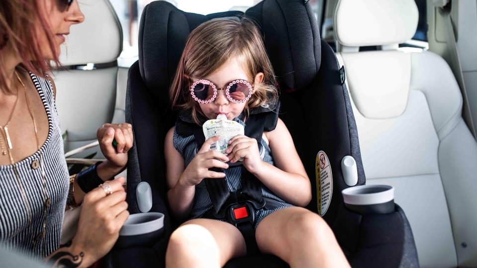 Little girl drinking a juice pouch while sitting in convertible car seat