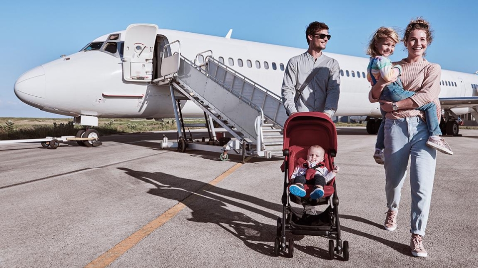 family walking away from airplane with stroller on sunny day