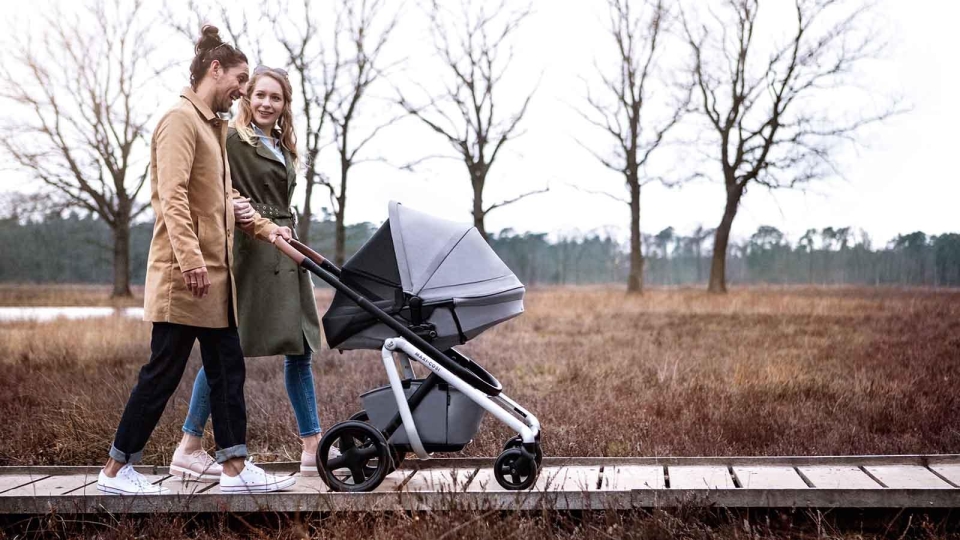 Family with baby in stroller walking in the rain